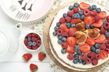 Beyaz ahşap masada servis edilen böğürtlenli lezzetli çikolatalı kek.