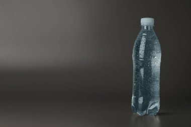 Gri arkaplanda plastik su şişesi, metin için boşluk