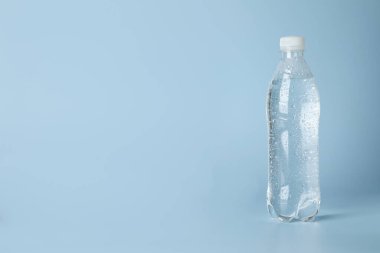 Açık mavi zemin üzerinde plastik su şişesi, metin için boşluk