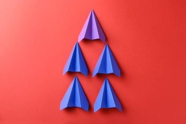 Kırmızı arkaplanda renkli kağıt uçaklar, üst görünüm