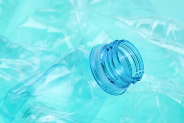 Turkuaz arka planda buruşmuş plastik şişeler, yakın plan.