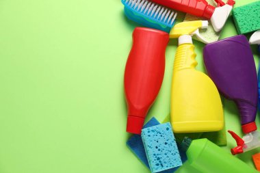 Yeşil arka planda farklı temizlik ürünleri ve araçlar, düz yatak. Metin için boşluk