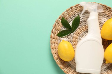 Turkuaz arka planda bir şişe temizlik malzemesi ve limon, üst manzara. Metin için boşluk