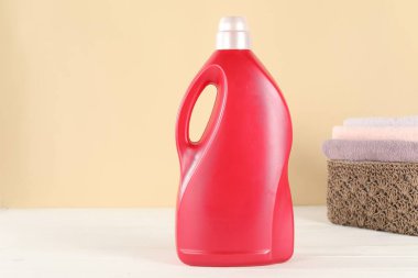 Beyaz ahşap masada bej arka planda çamaşır deterjanı şişesi