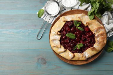 Kirazlı, nane ve pudra şekerli leziz galette açık mavi ahşap masa, düz uzanmış. Metin için boşluk