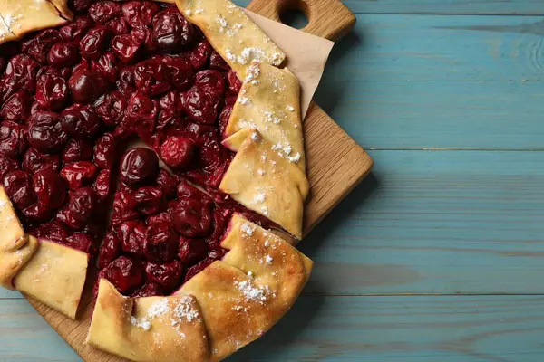 Açık mavi ahşap masadaki kirazlı leziz galette, üst manzara. Metin için boşluk