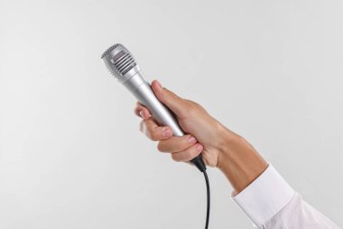 Açık gri arka planda mikrofonu olan adam, yakın plan.