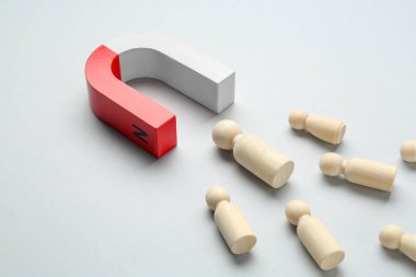 Mıknatıs açık gri arkaplanda insan figürlerini çekiyor, yakın plan