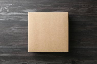 Ahşap arka planda boş bir karton kutu, üst manzara. Tasarım için model