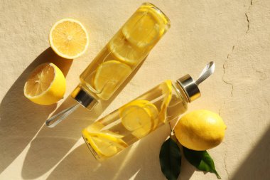 Şişe içinde limon suyu, taze meyve ve bej desenli arka planda yapraklar, düz uzanmış