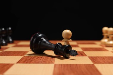 Beyaz piyon, satranç tahtasındaki siyah satranç kralına yakın, yakın plan. Rekabet konsepti