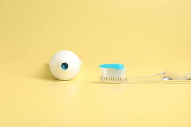 Diş fırçası, diş macunu ve sarı arka planda tüp.