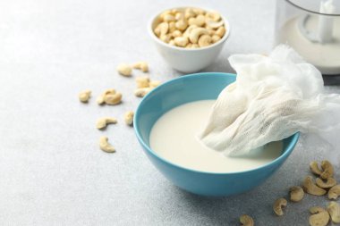 Ceviz sütü yapıyorum. Peynir bezi ve süt kasede fındıklar arasında kapalı bir masada, yakın plan. Metin için boşluk