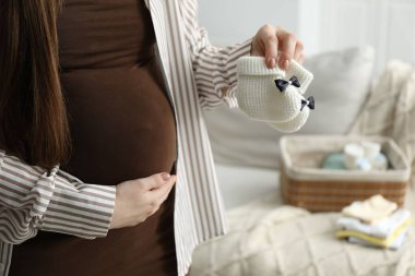 Pregnant woman with baby booties at home, closeup