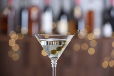 Arka planda bulanık zeytinli martini kokteyli, yakın plan. Bokeh etkisi
