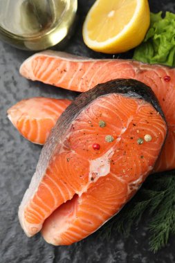 Taze çiğ somon bifteği, baharatlar ve ürünler koyu dokulu masa üzerinde, manzaranın üstünde.