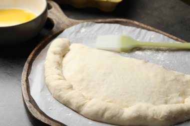 Gri masada pişmemiş calzone pizza, yakın plan.