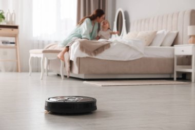 Anne kızıyla yatak odasında vakit geçiriyor. Robot elektrik süpürgesine odaklanıyor.