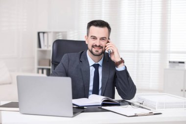 Ofiste akıllı telefondan konuşan mutlu bir bankacı.