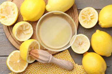 Taze limon suyu, sıkma makinesi ve ahşap masada meyveler.