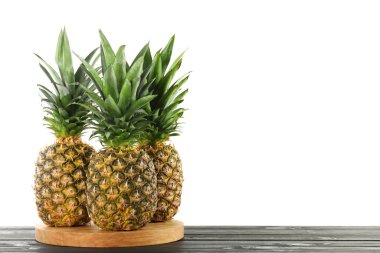 Tahta masada beyaz arka planda olgun ananaslar