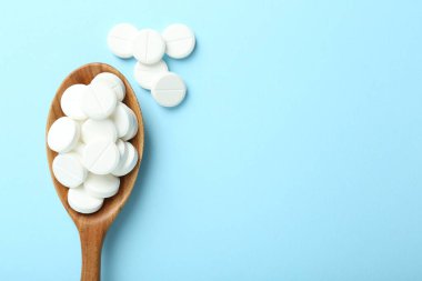 Antibiyotik haplar ve açık mavi arka planda kaşık. Metin için boşluk