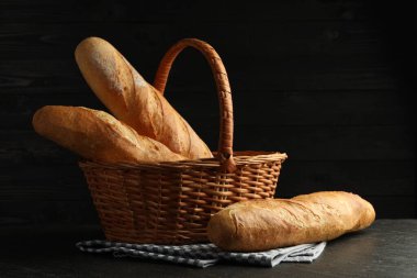 Siyah masanın üzerinde taze baget olan hasır sepet.