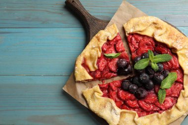 Çilekli, yaban mersinli ve açık mavi ahşap masadaki nane şekerli leziz bir galet. Metin için boşluk