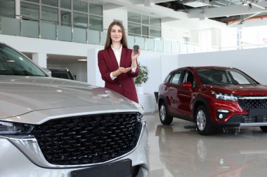 Kuaförde yeni gümüş arabanın yanında anahtarı tutan mutlu satıcı kadın.