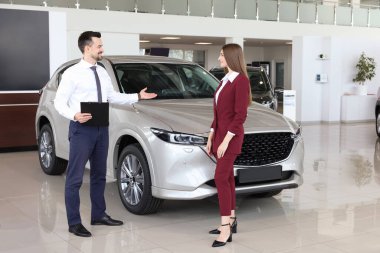 Satıcı ve müşteri salonda yeni arabanın yanında.