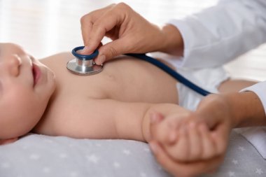 Pediyatrist, klinikte steteskoplu küçük bir çocuğu muayene ediyor. Bebeğin sağlığını kontrol ediyorum.