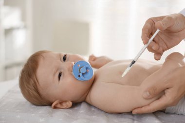 Pediyatrist klinikteki şirin bebeğe iğne yapıyor.