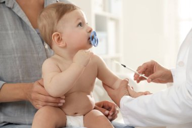 Pediyatrist klinikte bebek aşılıyor.