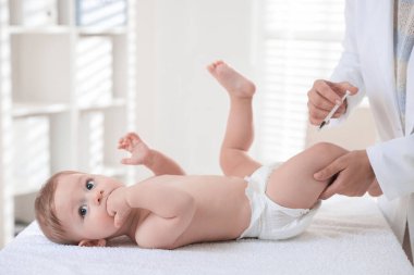 Pediyatrist klinikte bebek aşılıyor.