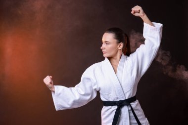 Kimonolu genç kadın karanlık arka planda karate çalışıyor, mesaj için yer var.