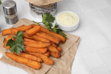 Tatlı patates kızartması, maydanoz ve sos beyaz fayanslı masada, yakın plan.