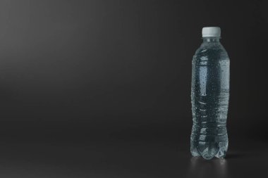 Gri arkaplanda plastik su şişesi, metin için boşluk
