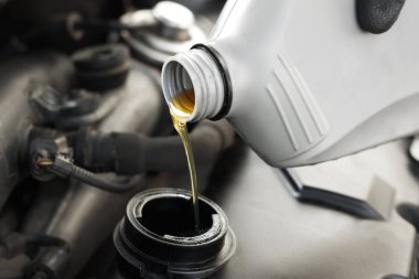 Araba motoruna motor yağı dökülüyor, yakın plan.