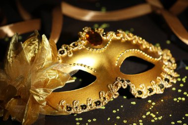 Güzel bir karnaval maskesi, koyu arkaplanda kurdele ve konfeti, yakın plan.