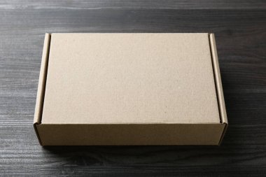 Ahşap arka planda boş bir karton kutu. Tasarım için model