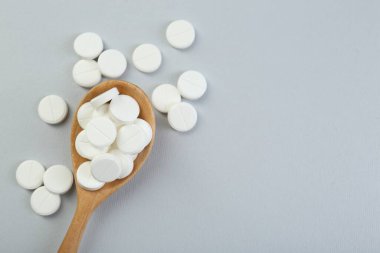 Antibiyotik haplar tahta kaşıkta gri arka planda, üst manzara. Metin için boşluk