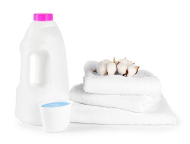 Çamaşır deterjanı, kep, temiz havlular ve beyaz üzerine izole edilmiş pamuk çiçekleriyle dolu bir şişe.