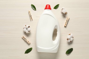 Çamaşır deterjanı, mandallar, pamuk çiçekler ve ahşap arka planda yeşil yapraklarla dolu bir şişe.