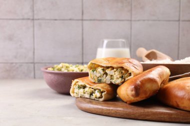 Delicious pirozhki (stuffed pastry pies) and ingredients on grey table, closeup. Space for text clipart