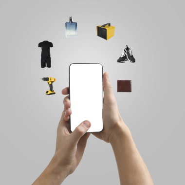 Açık gri arka planda cep telefonu kullanan bir adam, yakın plan. Farklı mallar etrafta uçuşuyor. Boş ekranlı aygıt