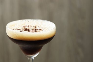Bulanık arka planda kahve çekirdekli enfes espresso martini, yakın plan. Metin için boşluk