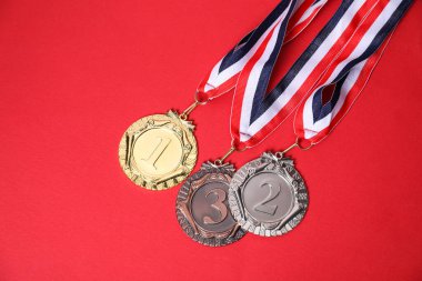 Kırmızı arka planda altın, gümüş ve bronz madalyalar.