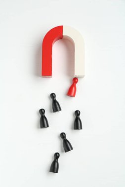 Beyaz arkaplan üzerinde renkli oyun parçaları çeken mıknatıs düz yatıyordu