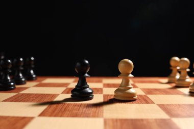 Satranç tahtasındaki diğer satranç taşlarının yanında siyah ve beyaz piyonlar. Rekabet konsepti