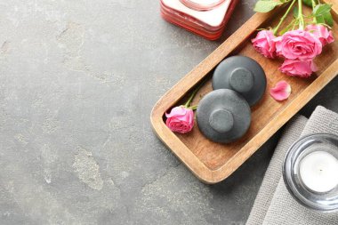 Spa taşları, gül çiçekleri ve gri masadaki mumlar, düz yatış. Metin için boşluk